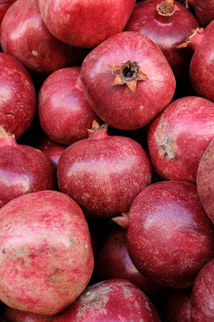 Lush, red pomegranates in a stacked arrangement. Ideal for food and freshness concepts.